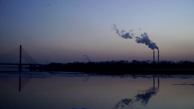 The-smoky-plant-on-the-background-of-the-river-and-the-setting-sun