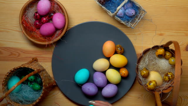 Woman's-hand-takes-colored-easter-eggs-from-different-baskets