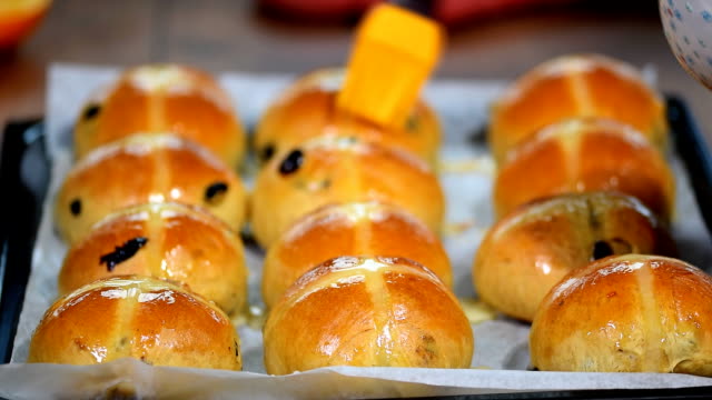 Homemade-Easter-traditional-hot-cross-buns.-Female-hands-cover-with-syrup.