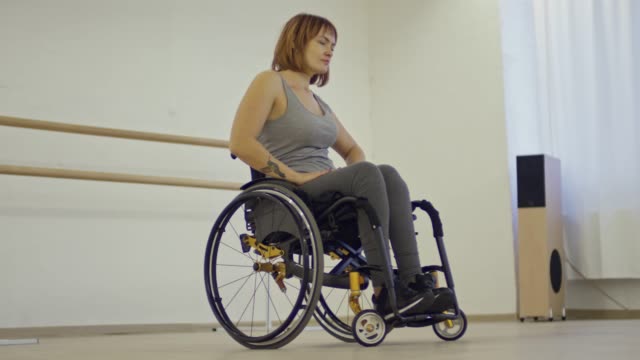 Junge-Frau-inspiriert-im-Rollstuhl,-die-Tanzschritte-lernen