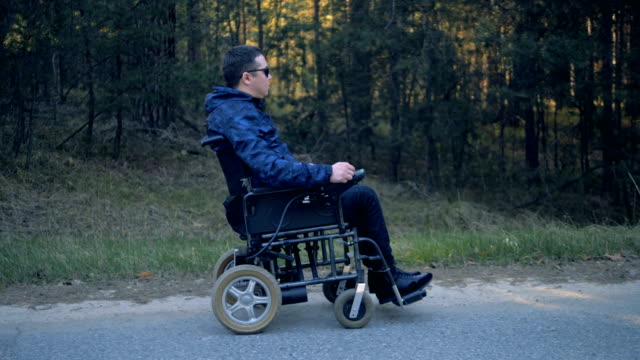 Man-in-a-wheelchair-enjoys-nature,-side-view.