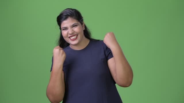 Junge-übergewichtige-schöne-indische-geschäftsfrau-vor-grünem-Hintergrund