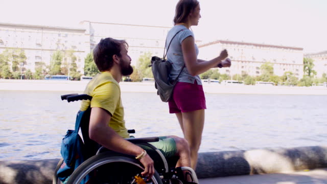 Young-disable-man-on-a-walk-near-the-river-with-his-wife