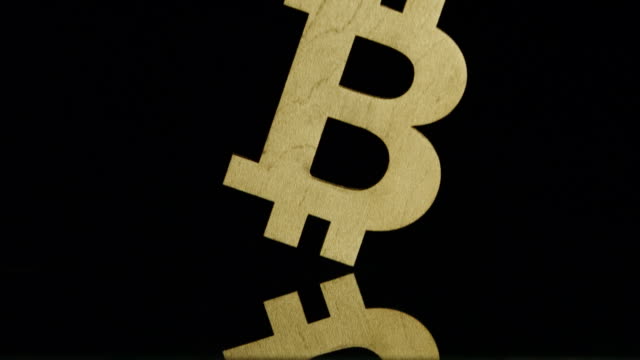 LANGSAM:-Golden-Bitcoin-Symbol-fällt-auf-schwarzem-Hintergrund