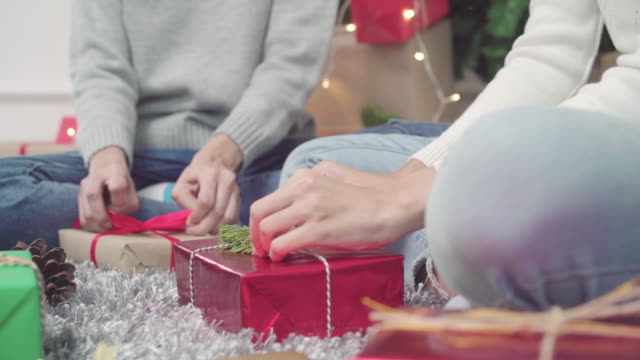 Lesben-Asian-paar-Verpackung-und-Verpackung-Weihnachtsgeschenk-schmücken-ihr-Wohnzimmer-zu-Hause-in-Christmas-Festival.-Lebensstil-Lgbt-Frauen-glücklich-feiern-Weihnachten-und-Neujahr-Konzept.