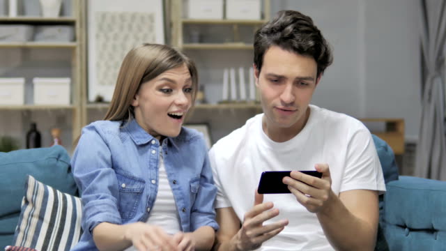 Animando-joven-pareja-excitada-de-éxito-mientras-que-la-observación-en-Smartphone