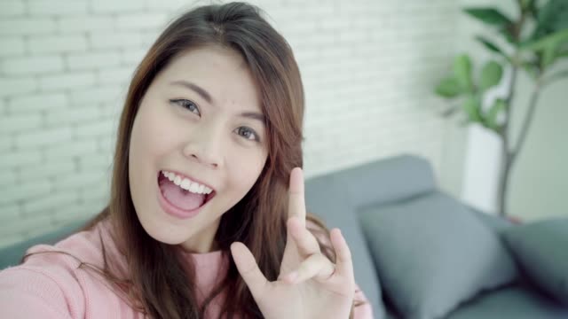 Asiatische-Blogger-Frau-mit-Smartphone-Videoaufnahme-Vlog-im-Wohnzimmer-zu-Hause,-weibliche-lustige-Momente-beim-liegen-auf-dem-Sofa-beim-Entspannen-zu-Hause.-Lifestyle-Blogger-machen-video-zu-Hause.