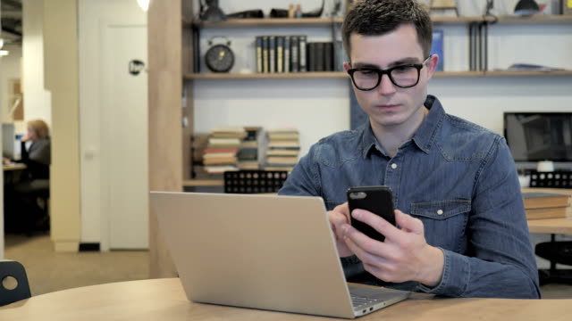 Hombre-creativo-en-vasos-con-teléfono-y-ordenador-portátil-para-el-trabajo
