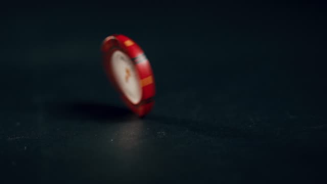 A-single-red-poker-chip-spins-in-slow-motion-until-it-falls-down.-Extreme-close-up.