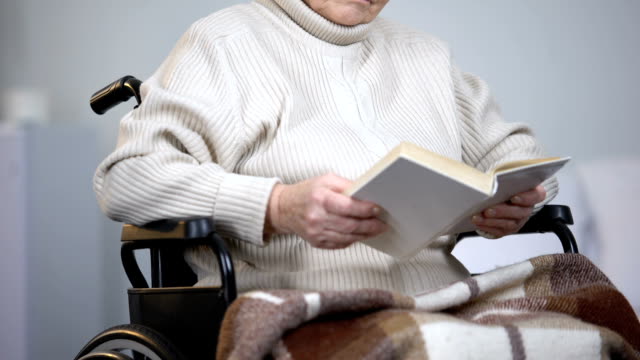 Sad-disabled-woman-in-eyeglasses-reading-book-in-nursing-home,-depression