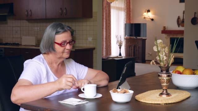 Seniorenfrau-mit-Kaffee-mit-digitalem-Tablet-PC
