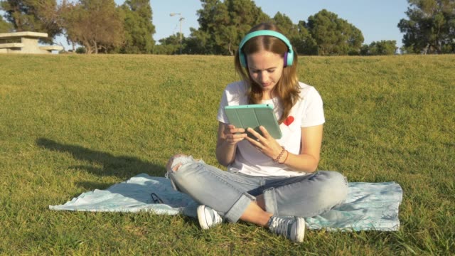 Teenager-arbeiten-mit-Tablet-im-Park