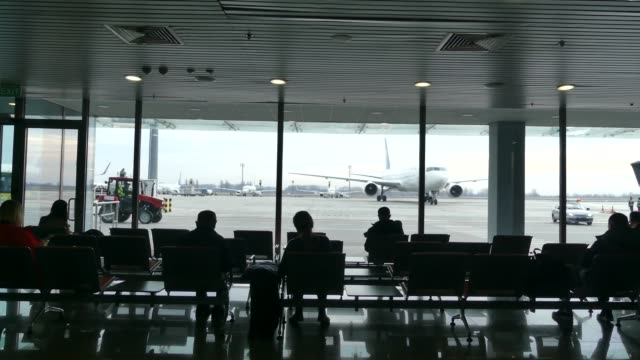 Passagiere-am-Flughafen-warten-auf-die-Einschiffung.-Passagiere-warten-auf-die-Landung-am-Flughafen.-Im-Hintergrund-ist-ein-Flugzeug.