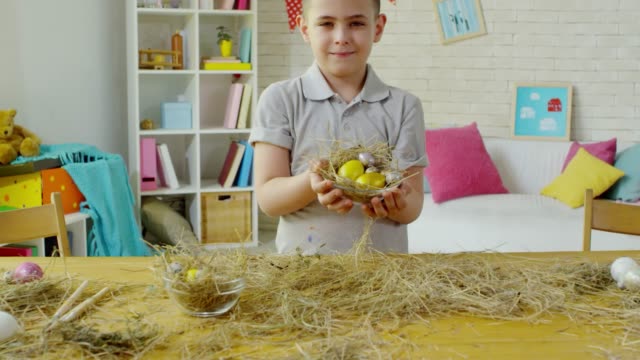 Lindo-niñito-posando-con-huevos-de-Pascua-en-hay-nido