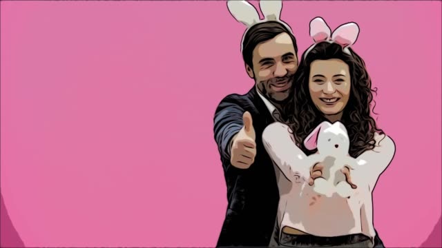 Young-creative-couple-on-pink-background.-With-bunny-ears-on-the-head.-For-this,-the-wife-holds-a-soft-toy-hare,-a-man-shows-a-class.-Give-a-sincere-smile.-Easter-concept.-Animation.