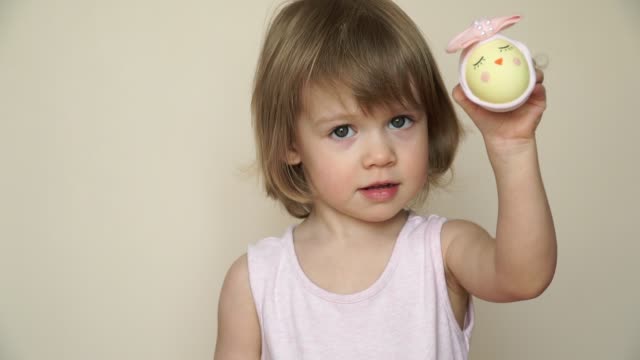 Portrait-of-cute-baby-girl-shows-chicken-egg-in-hands,-decorated-for-Easter-chick.