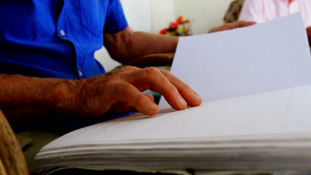 Mittelteil-des-blinden-Seniorenmanns,-der-ein-Braille-Buch-im-Pflegeheim-4k-liest
