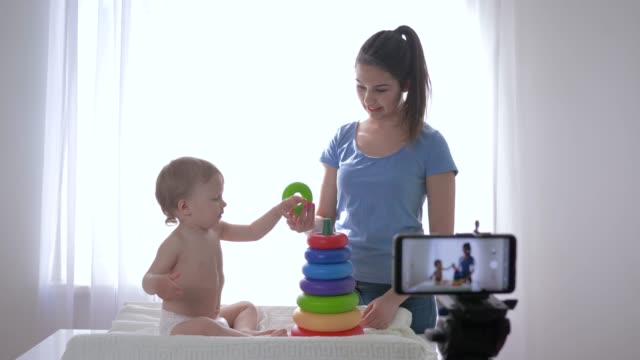Modernes-Marketing,-fröhlicher-Kinderjunge-mit-Mama-Blogger,-gespielt-von-pädagogischem-Spielzeug-während-der-Aufnahme-von-Online-Video-Blog-für-Anhänger-in-sozialen-Netzwerken-auf-Handy