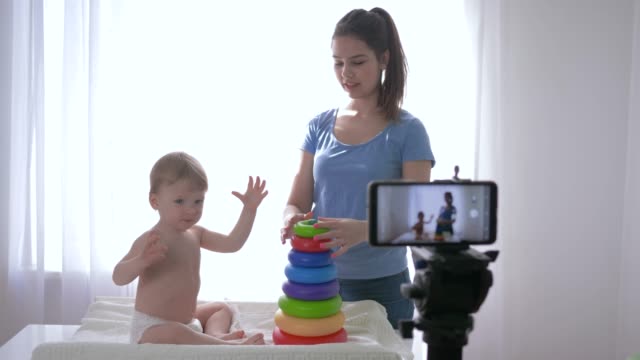 Videoblog,-Säugling-Junge-mit-Frau-von-pädagogischem-Spielzeug-gespielt-und-Aufzeichnung-von-Social-Media-Video-im-Streaming-live-auf-Handy-für-Abonnenten-in-sozialen-Netzwerken