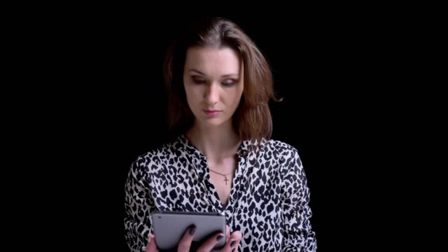 Closeup-portrait-of-young-stunning-caucasian-brunette-female-using-the-tablet-and-reacting-to-social-media-posts-in-front-of-the-camera