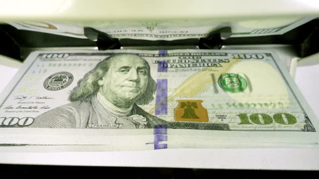 La-máquina-de-contador-de-dinero-electrónico-está-contando-es-contar-los-billetes-estadounidenses-de-dólares-estadounidenses-de-cien-dólares