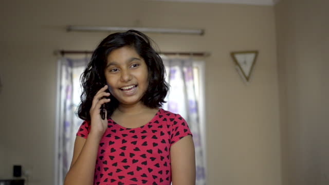 Cute-Indian-Asian-caucasian-happy-girl-child-having-fun-time-talking-to-friend-on-mobile-phone-call-front-view-portrait