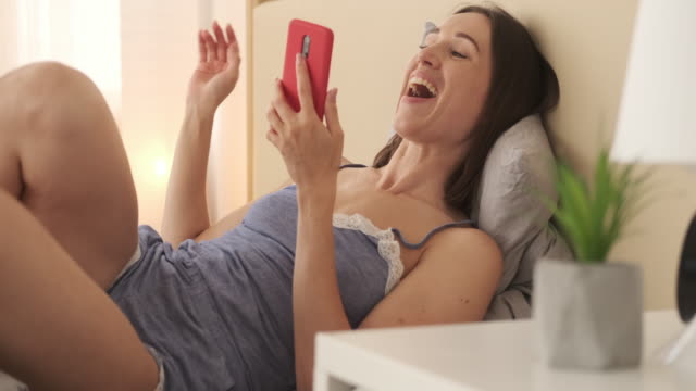 Entspannte-Frau-in-Nachtwäsche-genießen-Medieninhalte-auf-dem-Handy