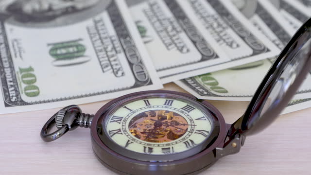 El-tiempo-es-dinero---un-reloj-de-bolsillo-en-un-fondo-de-billetes-de-cien-dólares