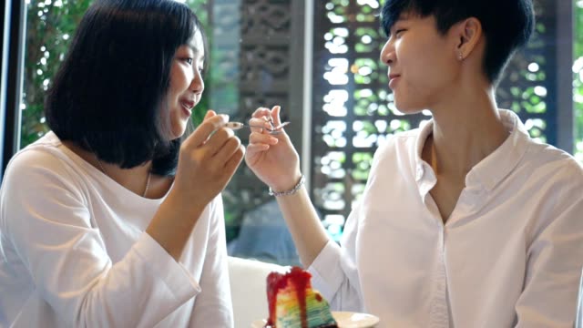 Joven-asiática-lesbiana-pareja-alimentando-dulce-arco-iris-pastel,-MOMENTO-LGBT-Amor-Slow-motion