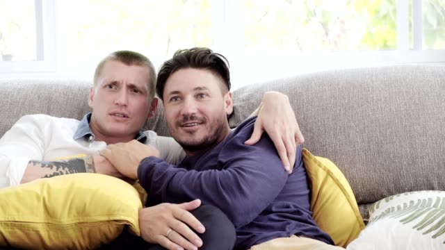 Gay-couple-relaxing-on-couch.-Enjoy-watching-tv,-jump-scare-mood.