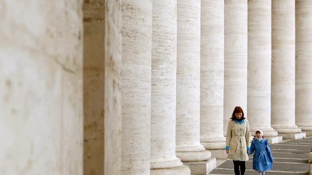 Frau-mit-ihrer-Tochter,-die-zwischen-den-Säulen-auf-der-Piazza-San-Pietro,-Vatikan,-spazieren-geht