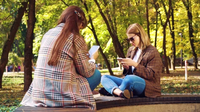 Hipster-Mädchen-surfen-Social-Media-auf-Smartphones-im-Freien