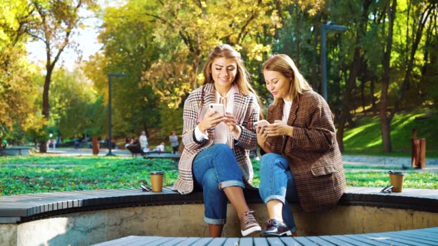 Fröhliche-Freunde-mit-Smartphones-draußen-im-öffentlichen-Park