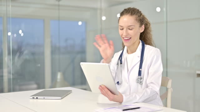 Junge-Ärztin-macht-Video-Chat-auf-Tablet-im-Büro