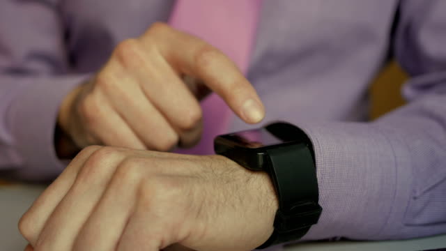 Man-using-his-smartwatch-app.-Closeup.-Businessman-using-trendy-smart-watches-mobile-application-on-touch-screen.-Guy-using-her-smartwatch-touch-screen-wearable-technology-device.-Close-Up.