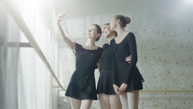 Tres-jóvenes-y-hermosas-Ballerinas-tomando-Selfie-en-un-estudio-luminoso-y-moderno.-Fuera-del-sol-está-brillando.-En-slow-motion.