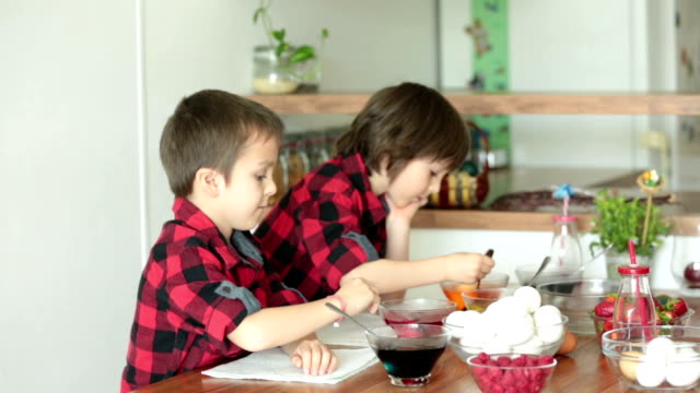 Dos-niños,-niños,-colorear-huevos-de-Pascua-en-casa,-comiendo-fresas