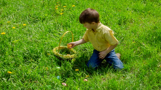 Boy-on-meadow-collect-the-colorful-easter-eggs