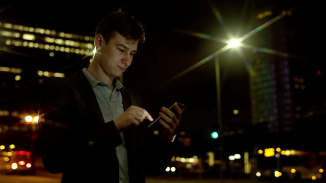 Hombre-guapo-joven-utiliza-su-smartphone-para-la-red-social-en-una-calle