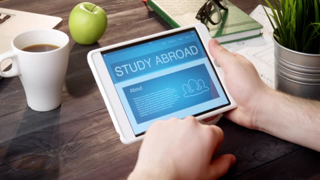 Studium-im-Ausland-Webseite-mit-digital-Tablette-am-Schreibtisch-zu-betrachten