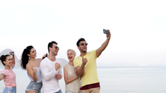 Personas-en-la-playa-tomando-Selfie-en-celulares-inteligentes-teléfonos,-joven-sonriente-grupo-de-turistas-felices-sonriendo