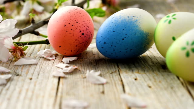 Huevos-de-Pascua-panorámica,-antigua-mesa-de-madera-y-pétalos-de-flor-de-almendra