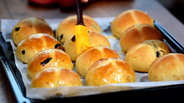 Homemade-Easter-traditional-hot-cross-buns.-Female-hands-cover-with-syrup.
