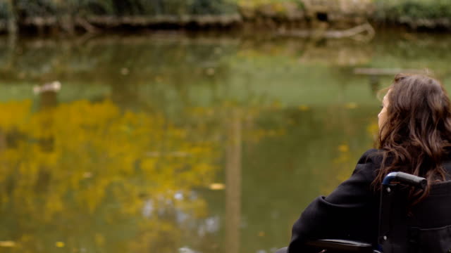 traurig-und-deprimiert-Frau-im-Rollstuhl-betrachtet-den-See