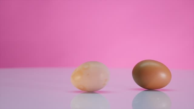 Zwei-Eiern-drehen-auf-einem-Tisch-auf-einem-rosa-Hintergrund