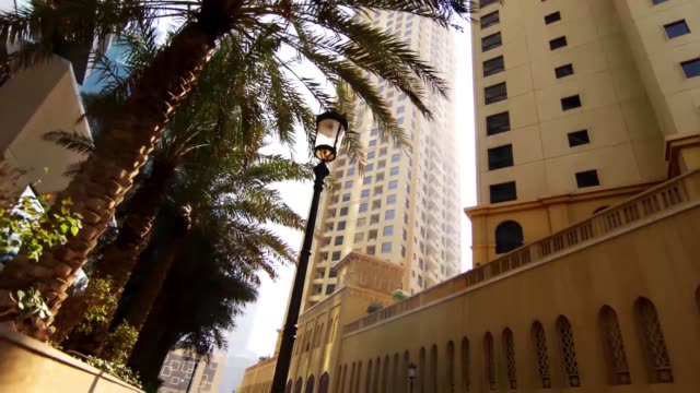 Wide-road-with-tall-palms-and-modern-buildings.-Stock.-Palm-trees-and-typical-retro-art-deco-style-buildings