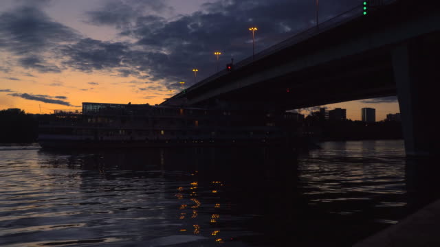 Blick-auf-die-Stadt-bei-Sonnenuntergang-mit-einem-Schiff-unter-der-Brücke