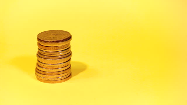die-Hand-Stapeln-verschiedener-Münzen-auf-einem-farbigen-Hintergrund