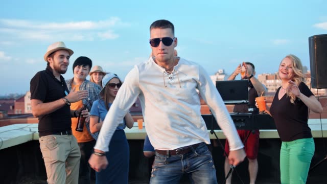 Hombre-europeo-activo-en-gafas-de-sol-que-se-divierten-bailando-en-medio-de-la-pista-de-baile-de-fiesta-en-la-azotea