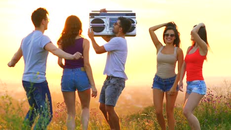 The-young-people-with-a-boom-box-dancing-on-a-sunset-background.-slow-motion
